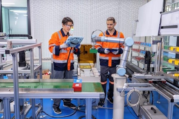 Zwei Fachkräfte bedienen einen kollaborativen Roboter an einer Montagelinie