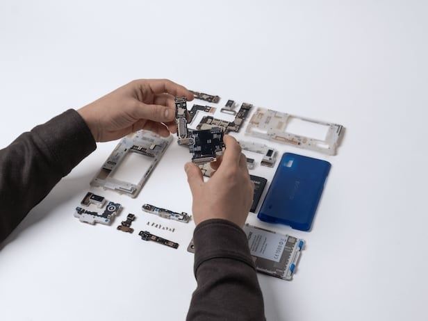 Hände zerlegen ein Smartphone in einzelne Module und Bauteile