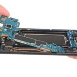 Geöffnetes Smartphone mit herausgelöster Platine und sichtbaren Bauteilen